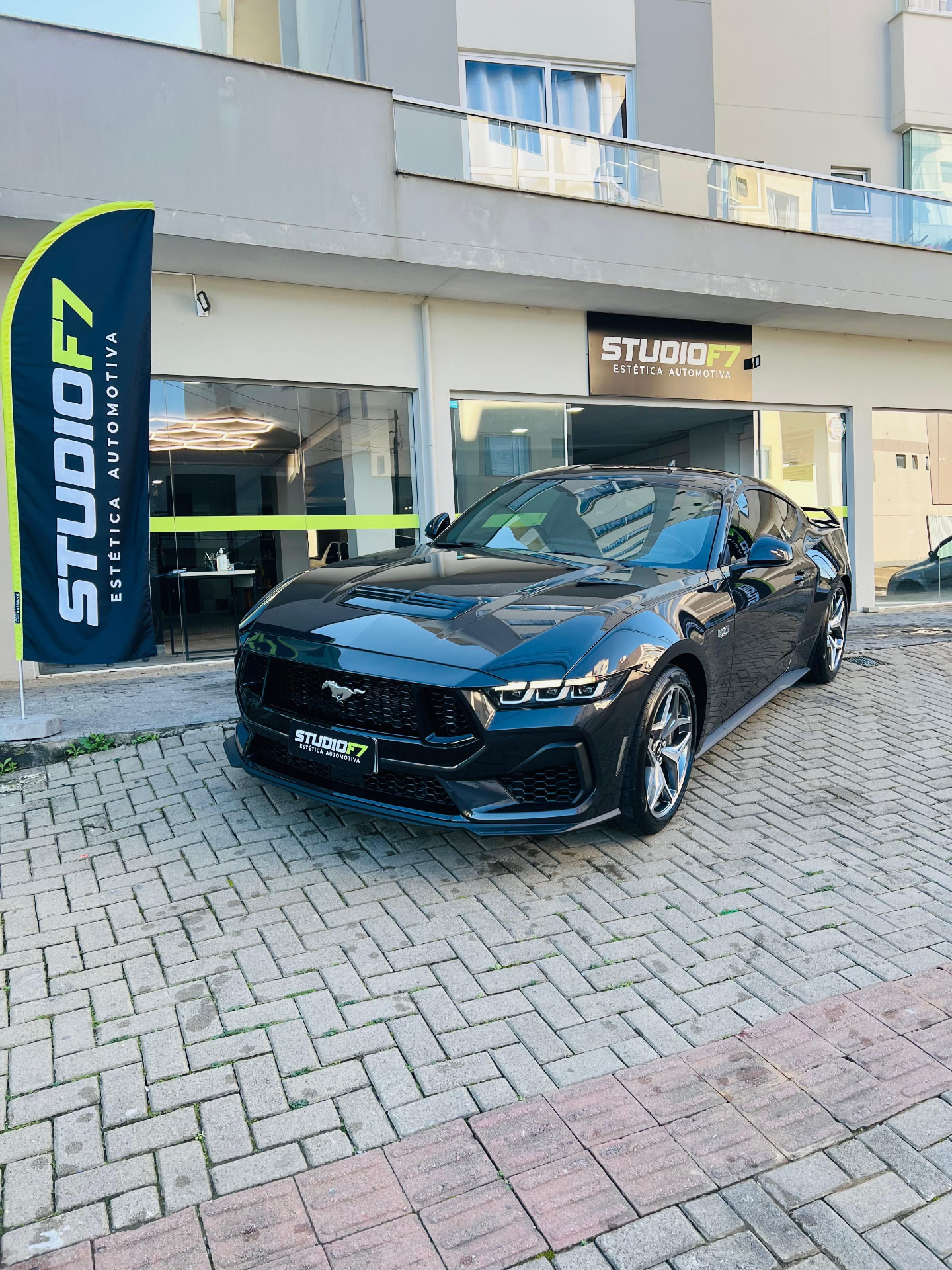 Ford Mustang preto estacionado em frente à fachada da StudioF7