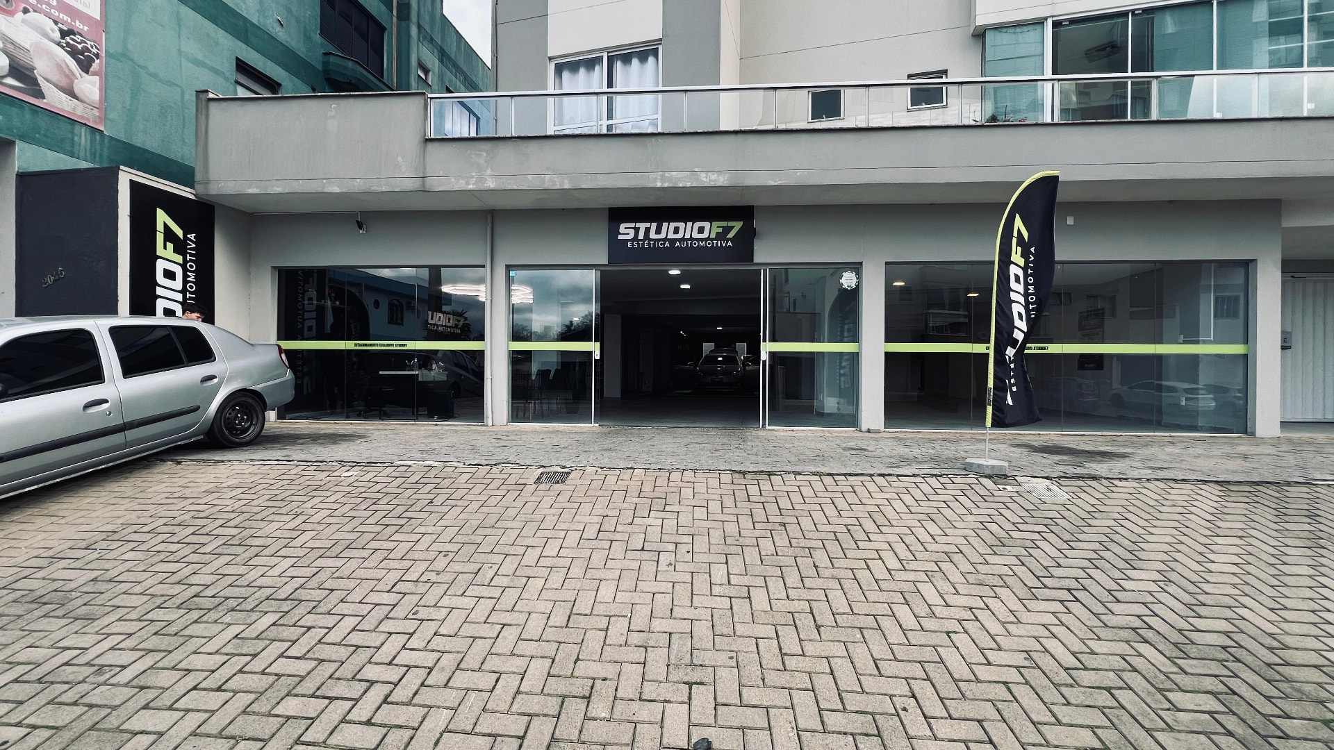 Fachada externa da StudioF7 Estética Automotiva com wind banner e vidraças