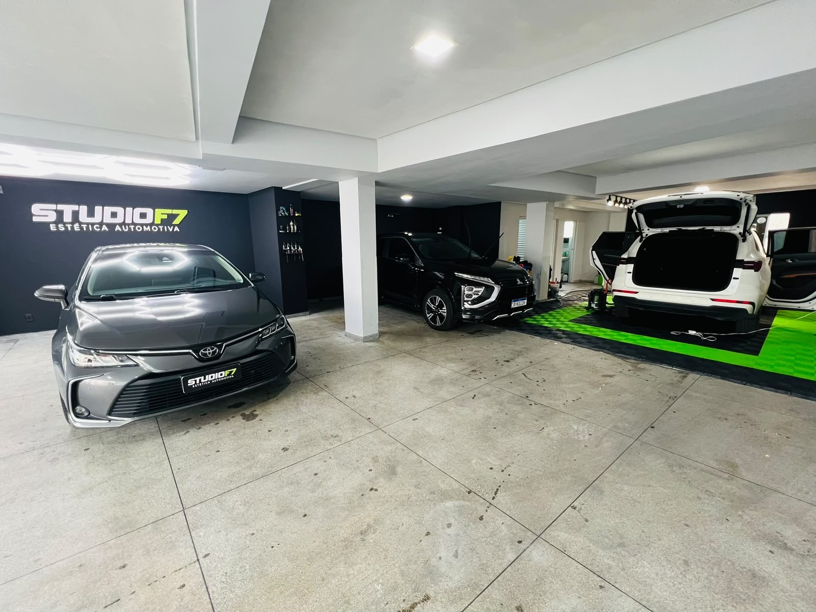 Garagem da StudioF7 com Toyota Corolla, Mitsubishi Eclipse Cross e SUV branco em atendimento
